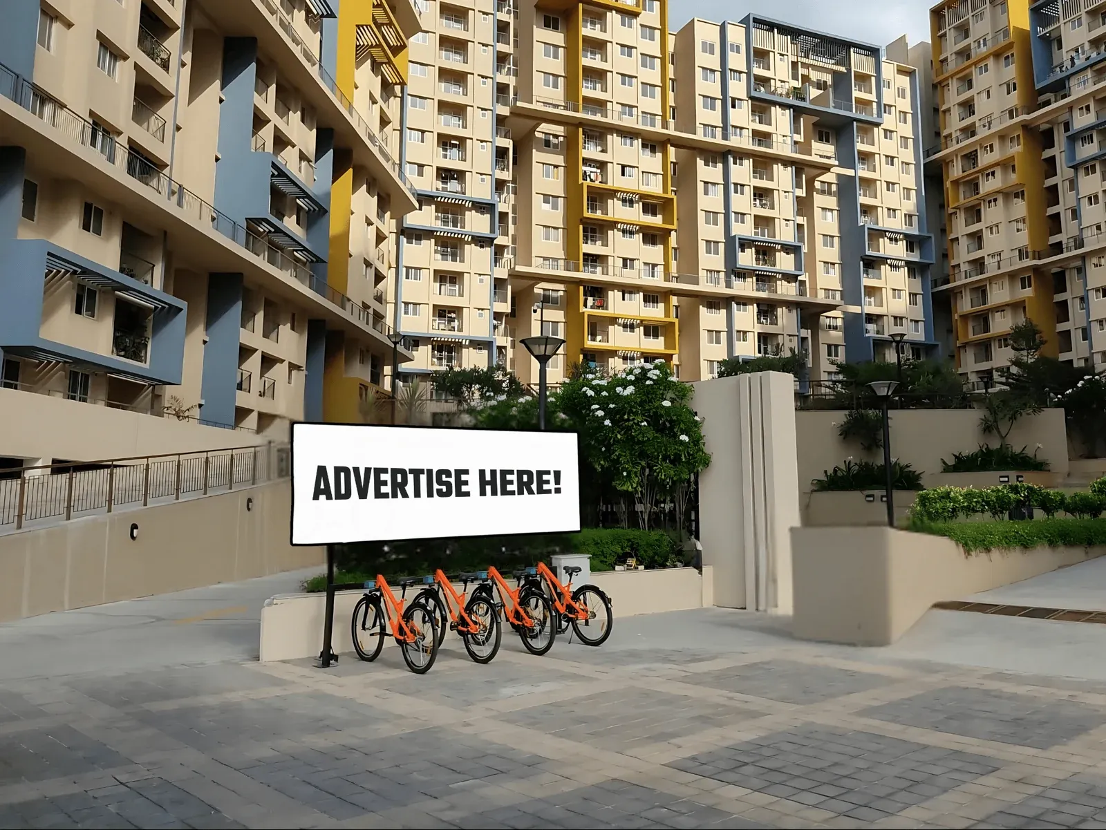 A large Tilt billboard next to orange Tilt bicycles at the entrance of a gated community
